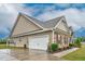 Exterior side view showcasing a two-car garage with stone and siding combination and driveway at 3909 Mendenhall Dr, Zebulon, NC 27597