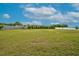 Large grassy yard with distant houses surrounded by lush greenery and a clear blue sky at 3909 Mendenhall Dr, Zebulon, NC 27597