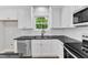 Bright kitchen featuring white cabinets, stainless steel dishwasher, black countertops, and a window view at 401 N Raiford St, Selma, NC 27576