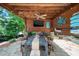 Covered outdoor dining area with a rustic wooden table, ceiling fan, and mounted TV for outdoor gatherings at 404 Brightling Way, Holly Springs, NC 27540