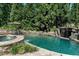 Serene pool area featuring a rock waterfall, lush landscaping, and a tranquil spa for ultimate relaxation and enjoyment at 404 Brightling Way, Holly Springs, NC 27540