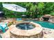 Backyard pool and spa are surrounded by lush greenery and beautiful stonework at 404 Brightling Way, Holly Springs, NC 27540