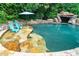 Inviting backyard pool features a rock waterfall and serene seating area at 404 Brightling Way, Holly Springs, NC 27540