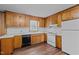 Kitchen with wood cabinets, white appliances, and modern flooring at 407 W Depot St, Angier, NC 27501