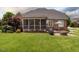 A spacious backyard with a screened-in porch, patio furniture, and a brick firepit, perfect for outdoor entertaining at 4266 Aviemore Run, Burlington, NC 27215