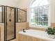 Bright bathroom with tiled walls, bathtub, shower and a large window at 4266 Aviemore Run, Burlington, NC 27215