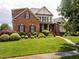 Charming brick home with lush landscaping, mature trees, and a welcoming front porch, creating a delightful curb appeal at 4266 Aviemore Run, Burlington, NC 27215