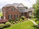 Beautiful brick home with manicured lawn, blooming bushes, and a winding walkway leading to the inviting front entrance at 4266 Aviemore Run, Burlington, NC 27215