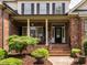 Inviting front porch with brick columns and steps, featuring dark accents and manicured landscaping at 4266 Aviemore Run, Burlington, NC 27215