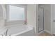 Bathroom with a tub and shower behind glass doors in a brightly lit room at 5292 Goosecross Way, Fuquay Varina, NC 27526