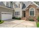 Close-up view of the home's entrance highlighting stone details, a two-car garage, and manicured greenery at 5410 Highcroft Dr, Cary, NC 27519