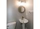 Powder room with pedestal sink, round mirror, and modern lighting fixtures at 5410 Pageford Dr, Durham, NC 27703
