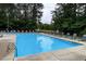 Relaxing community pool surrounded by chairs and lush greenery for residents to enjoy at 5410 Pageford Dr, Durham, NC 27703