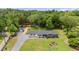 Aerial view of a single-story home with a large yard, mature trees, and detached garage at 553 Isley Rd, Haw River, NC 27258