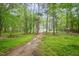 A pathway leading through the wooded backyard towards the house at 553 Isley Rd, Haw River, NC 27258
