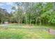 Fenced backyard featuring a grassy lawn, mature trees, and an outbuilding at 553 Isley Rd, Haw River, NC 27258