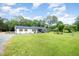 Single-story home with a well-manicured lawn, mature trees, and a detached garage at 553 Isley Rd, Haw River, NC 27258