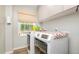 Well-lit laundry room with modern appliances and convenient upper cabinets for storage, next to window at 553 Isley Rd, Haw River, NC 27258