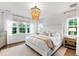 Light-filled bedroom with a large window, decorative chandelier, light walls, and hardwood floors at 729 Mills St, Raleigh, NC 27608