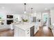 Bright, white kitchen with island, stainless steel appliances, and hardwood floors open to a living room with fireplace at 729 Mills St, Raleigh, NC 27608