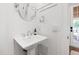 Elegant powder room with pedestal sink, round mirror, stylish fixtures, and access to the front porch at 729 Mills St, Raleigh, NC 27608
