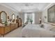 Comfortable main bedroom features a tray ceiling, large window, and decorative mirrors and accents at 79 Heatherwood Dr, Chapel Hill, NC 27516
