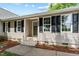 Close-up of home's front entrance featuring black-shuttered windows and meticulously maintained landscaping at 800 Linens St, Graham, NC 27253