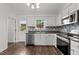 Clean kitchen featuring stainless steel appliances, white cabinets, decorative backsplash, and access to the backyard at 800 Linens St, Graham, NC 27253