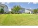 Landscaped backyard featuring a stone patio, outdoor kitchen, fire pit, and grassy area at 805 Narrative Ln, Durham, NC 27703
