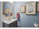 Stylish powder room with blue walls, elegant mirror, vanity, and framed butterfly artwork at 805 Narrative Ln, Durham, NC 27703