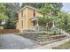 Two-story yellow home showing side yard and driveway, surrounded by mature trees and landscaping at 813 Burch Ave, Durham, NC 27701