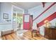 Inviting foyer with hardwood floors, red-painted stairs, rocking chair and access to the porch at 813 Burch Ave, Durham, NC 27701