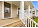 Inviting covered front porch with wood decking, white columns and railings, and a brown front door at 825 Abbyberry Dr, Wake Forest, NC 27587