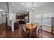 Open dining area with modern chandelier, dark wood floors, and adjacent kitchen at 831 Poplar St, Durham, NC 27703