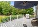 Outdoor deck with patio umbrella, grill, and views of the backyard and surrounding trees at 9013 Dansforeshire Way, Wake Forest, NC 27587