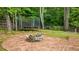 Backyard with a stone patio with a fire pit feature, surrounded by green yard and mature trees at 9013 Dansforeshire Way, Wake Forest, NC 27587