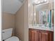 Half bathroom with wood vanity, decorative mirror and traditional toilet, freshly painted in neutral colors at 9013 Dansforeshire Way, Wake Forest, NC 27587