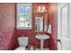 Charming half bathroom with vibrant floral wallpaper, pedestal sink, and a gold-framed mirror at 102 Lions Mouth Ct, Cary, NC 27518