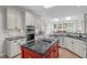 Large kitchen with white cabinets, stainless steel appliances, and a red island cooktop under two skylights at 102 Lions Mouth Ct, Cary, NC 27518