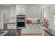 Updated kitchen showcasing white cabinets, granite countertops, stainless steel appliances, and a stylish tile backsplash at 102 Lions Mouth Ct, Cary, NC 27518