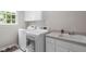 Bright laundry room featuring a washer and dryer, complemented by ample storage and a convenient utility sink at 102 Lions Mouth Ct, Cary, NC 27518