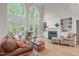 Bright living room featuring two-story windows, fireplace, and access to the deck from the large glass doors at 102 Lions Mouth Ct, Cary, NC 27518