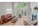 Bright living room featuring two-story windows, fireplace, and access to the deck from the large glass doors at 102 Lions Mouth Ct, Cary, NC 27518