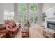 Bright living room featuring two-story windows, fireplace, and access to the deck from the large glass doors at 102 Lions Mouth Ct, Cary, NC 27518