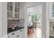 Pantry area with glass door cabinets, granite countertops, and a view to the chandelier-lit dining room at 102 Lions Mouth Ct, Cary, NC 27518