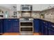 Close up of modern kitchen area featuring a stainless steel range and granite counters, complemented by stylish blue cabinets at 102 Westside Dr, Chapel Hill, NC 27516