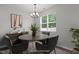 Virtually staged dining room features modern chandelier, round table, and window with natural light at 1028 Gallivant Way, Wake Forest, NC 27587
