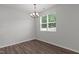 Bright dining room features a modern chandelier, large window and attractive dark hardwood floors at 1028 Gallivant Way, Wake Forest, NC 27587