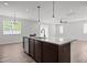 Open kitchen with a granite island and sink, flowing into the living area with natural light at 1028 Gallivant Way, Wake Forest, NC 27587