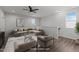 Virtually staged living room features a sectional sofa, hardwood floors, and a modern ceiling fan at 1028 Gallivant Way, Wake Forest, NC 27587